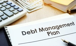 A Visual Guide to Successful Debt Management plan A pen and calculator are placed on a desk, highlighting the visual representation of a debt management plan